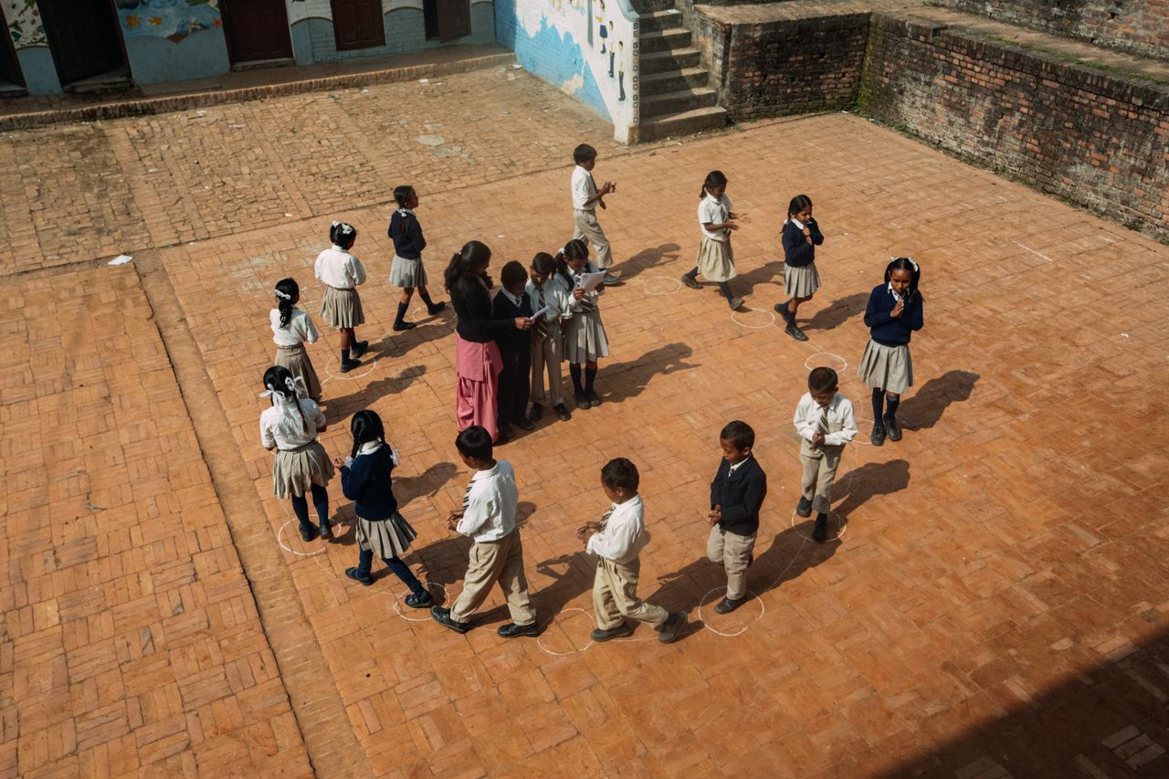 Aerial view of children playing a game on the school courtyard during daytime.